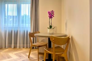 stół z 2 krzesłami i waza z fioletowymi kwiatami w obiekcie Villa Bea w Bratysławie