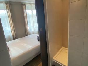 ein kleines Schlafzimmer mit einem Bett und einer Dusche in der Unterkunft La Pause Voyage in Bourbourg