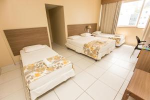 um quarto de hotel com duas camas e uma mesa em Rede Andrade Barra em Salvador