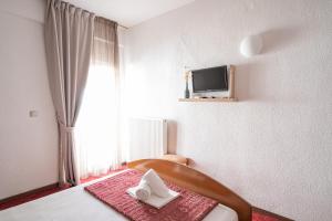 a bedroom with a bed with a tv on the wall at Hotel Akropol in Paralia Katerinis