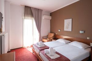 a hotel room with two beds and a window at Hotel Akropol in Paralia Katerinis