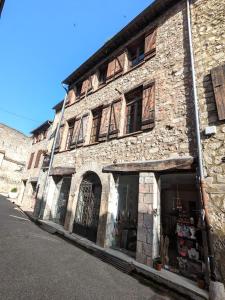 un vieux bâtiment en pierre avec un magasin dans une rue dans l'établissement Appartement Saint Jean 2 Cosy et Confort, à Villefranche-de-Conflent