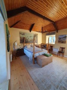 a bedroom with a large bed with a wooden ceiling at Driftwood Cottage in Yelverton