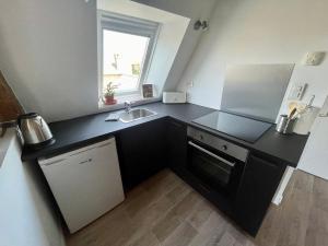 een keuken met een zwart aanrecht en een wastafel bij Appartement cosy vue sur le vignoble in Sancerre
