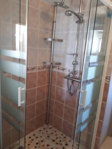 eine Dusche mit Glastür und Fliesenboden in der Unterkunft Gîte Pouton in Saint-Loubouer