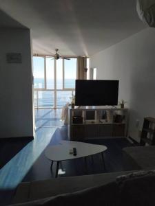 ein Wohnzimmer mit einem TV und einem Couchtisch in der Unterkunft Beachfront apartment in Estepona