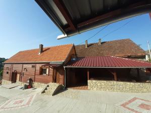 une maison avec un toit rouge et un bâtiment dans l'établissement Dvokrevetne Sobe - Snežana, à Ležimir