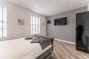 a white bedroom with a bed and a flat screen tv at Tanna Estates - Ranelagh Terrace House in Leamington Spa