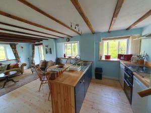 a large kitchen with blue walls and wooden beams at Driftwood Cottage in Yelverton