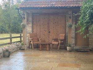 a wooden pavilion with two chairs and a table at Character 1 bedroom country annex in West Camel in Yeovil