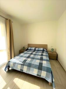 a bedroom with a bed with a plaid blanket on it at Affittimoderni La Maddalena - MADA03 in La Maddalena