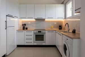 a white kitchen with white cabinets and a dishwasher at Island Hills in Rhodes Town
