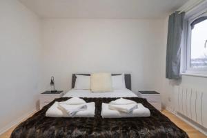 a white bedroom with a large bed with towels on it at 1BD Flat - Prime Location Surrey Quays in London