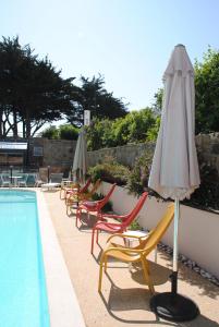 a row of chairs and an umbrella next to a swimming pool at Le Churchill Hôtel & Spa in Carnac