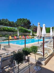 a swimming pool with umbrellas and tables and chairs at Le Churchill Hôtel & Spa in Carnac