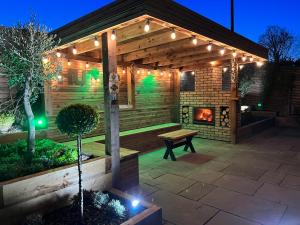 a wooden pergola with a bench and a fireplace at 1 The Cottage in Upholland