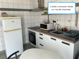 eine Küche mit einem weißen Kühlschrank und einer Mikrowelle in der Unterkunft La Pause Voyage in Bourbourg