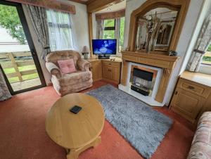 a living room with a table and a fireplace at 55 Glenfinart Caravan Park in Dunoon