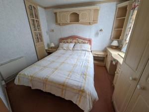 a small bedroom with a bed with a striped blanket at 55 Glenfinart Caravan Park in Dunoon