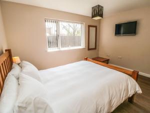 a bedroom with a white bed and a television at 31A The Green in Scarborough