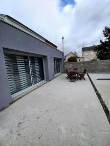 a patio with a table and a bench next to a building at Magnifique maison à 5 mns du circuit des 24h à pieds in Le Mans