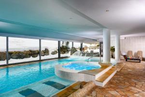 uma grande piscina numa casa com janelas em Carlo Magno Hotel Spa Resort em Madonna di Campiglio