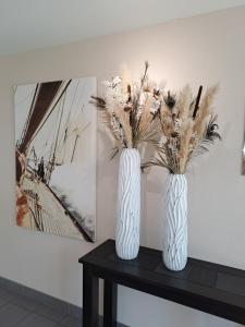 two white vases with flowers sitting on a table at Le Churchill Hôtel & Spa in Carnac