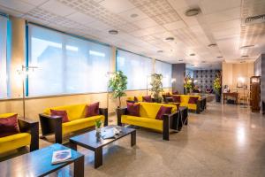 una sala d'attesa con divani e tavoli gialli di Hotel Parisi a Nichelino