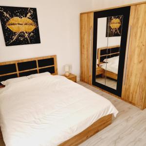 um quarto com uma cama branca e um espelho em Comfort cosmopolis em Ştefăneştii de Jos