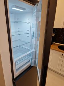 an empty refrigerator with its door open in a kitchen at Comfort cosmopolis in Ştefăneştii de Jos