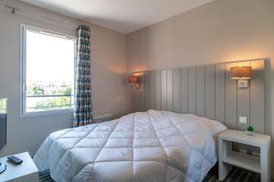 a bedroom with a large white bed and a window at Les Thermes 521 - Appt proche plage avec piscine partagée in Concarneau +5 photos