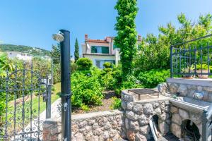 a garden with a stone fireplace in front of a house at Apartments Rada i Stanislav in Barbat na Rabu