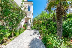 a walkway in front of a house with a palm tree at Apartments Rada i Stanislav in Barbat na Rabu