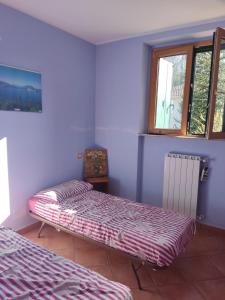 2 camas en una habitación con paredes y ventanas moradas en Casa Marianne, en Osmate Lentate