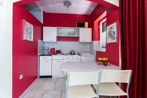 a kitchen with red walls and a table and chairs at Apartments Rada i Stanislav in Barbat na Rabu