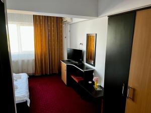 a hotel room with a bed and a television at Hanul Kartali in Lumina