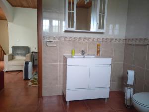 a bathroom with a white sink and a chair at Casa dos Avós in São Roque do Pico