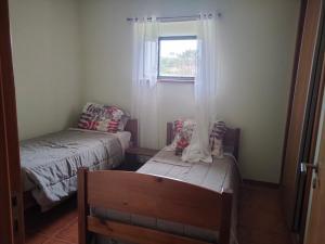 サン・ロケ・ド・ピコにあるCasa dos Avósのベッド2台と窓が備わる小さな客室です。