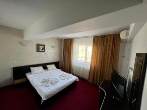 une chambre d'hôtel avec un lit et une télévision dans l'établissement Hanul Kartali, à Lumina