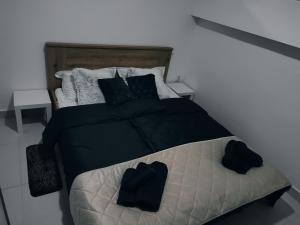 1 dormitorio con 1 cama con almohadas negras en Apartman Katy, en Sremska Mitrovica
