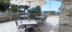 eine Terrasse mit Tischen, Stühlen und einem Sonnenschirm in der Unterkunft Casa vacanze da Cristina app C in Maratea