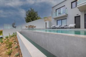 a swimming pool in front of a house at Anadeo Villas & Suites in Exanthia