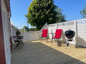 a deck with red chairs and a grill on it at Lyckan - Minihus i lantlig miljö in Ulricehamn