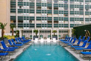a pool with blue chairs and a building at Sonder at Commerce in Dallas
