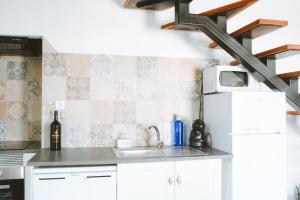 a kitchen with white cabinets and a sink at Casita do Castelo in Lourinhã