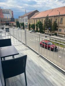 a balcony with a table and a car on a street at ArtMotel & Bistro in Haţeg