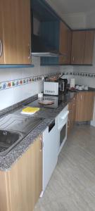 a kitchen with wooden cabinets and a counter top at Piso As Rodas in Villanueva de Arosa