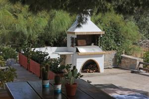 a outdoor fireplace in a garden with a table and cactus at Pine Cottage, Syros Island in Firókambos