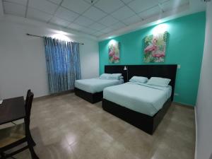 2 łóżka w pokoju z niebieskimi ścianami i stołem w obiekcie Hotel Coronado Inn w mieście Playa Coronado