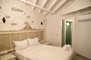 a bedroom with a bed and a wall with rocks at Alacati Gubiba Evleri in Alacati